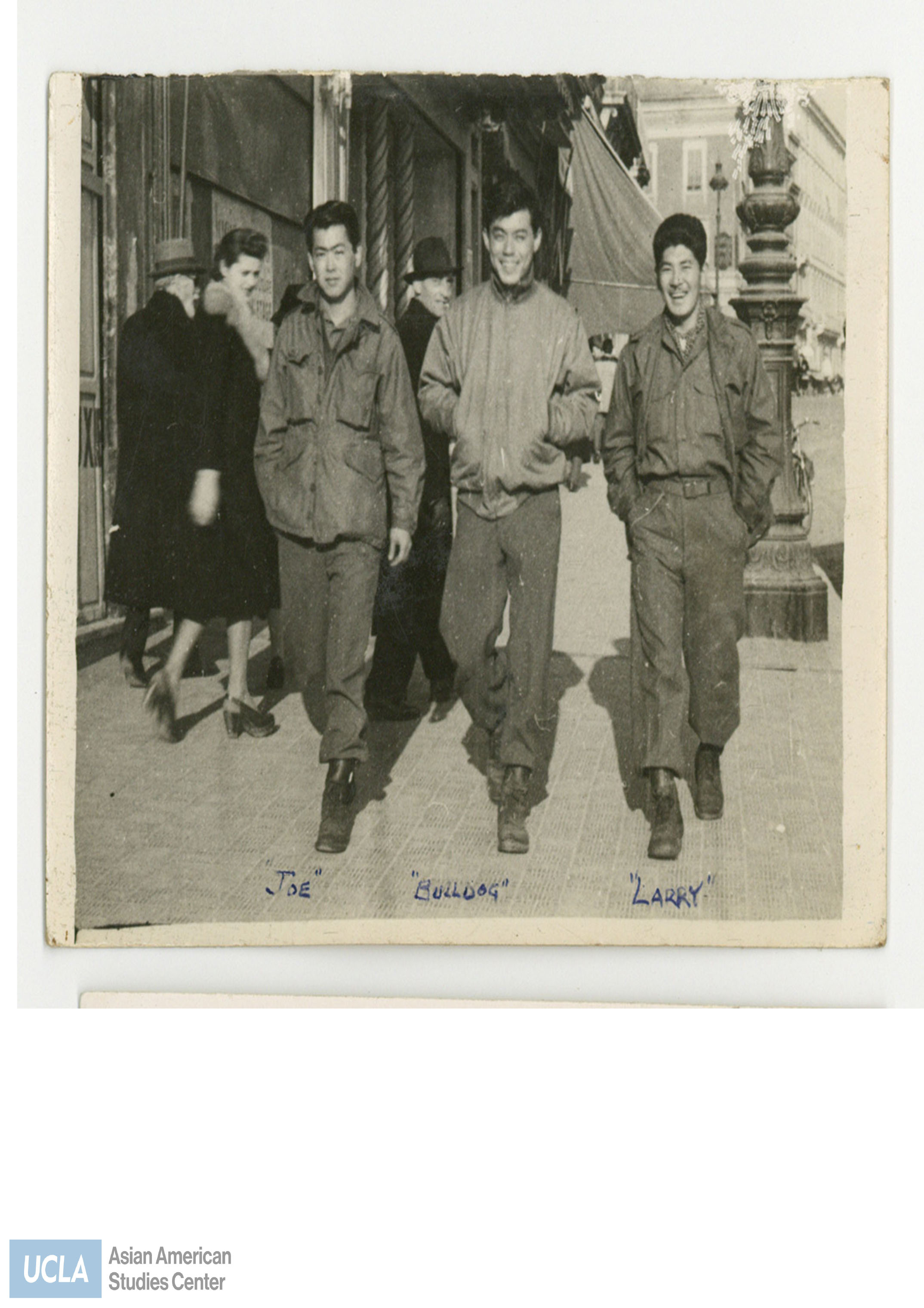 Photo of Nisei men walking down the street in France. Back of photo includes text: 