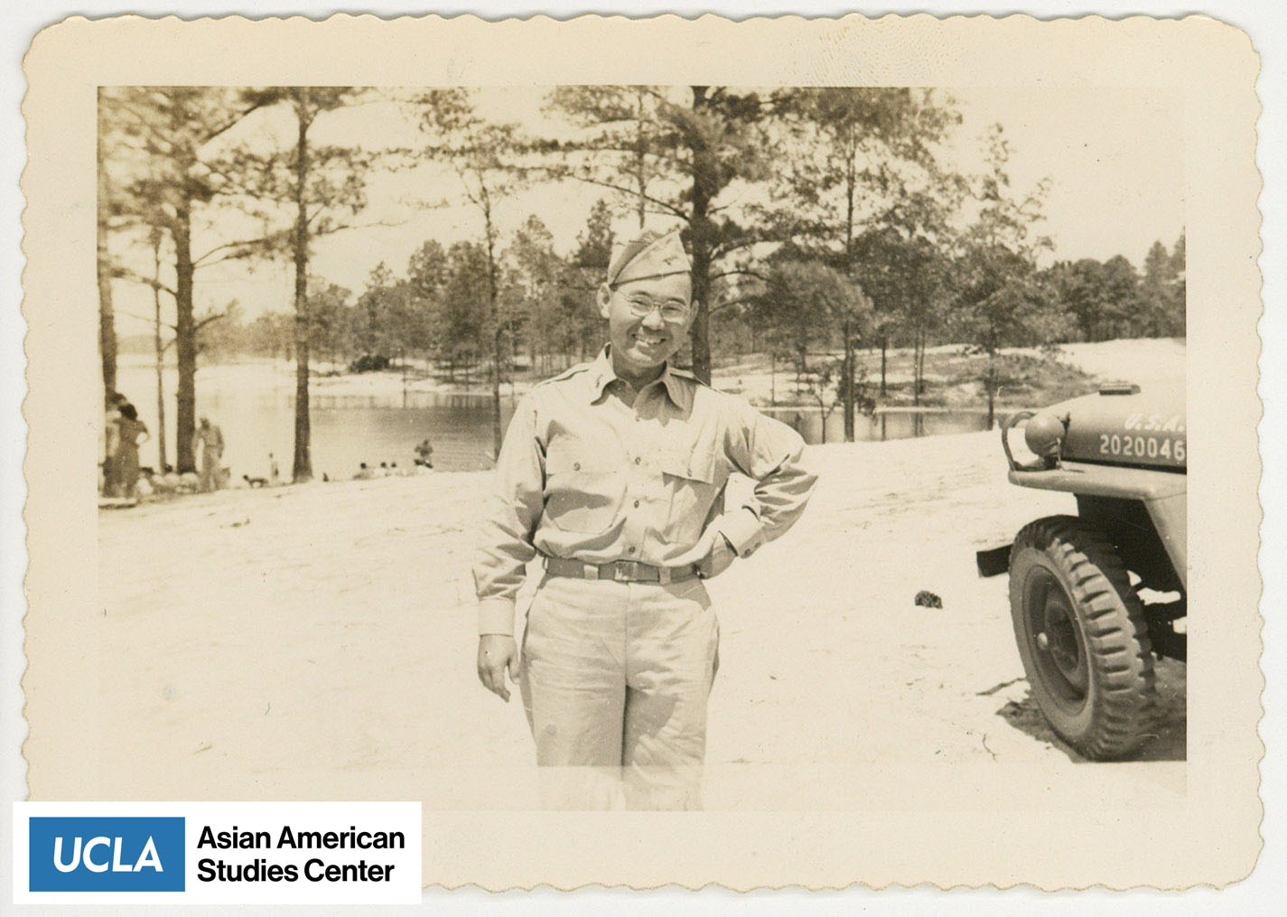 Man in army uniform standing infront of a lake.