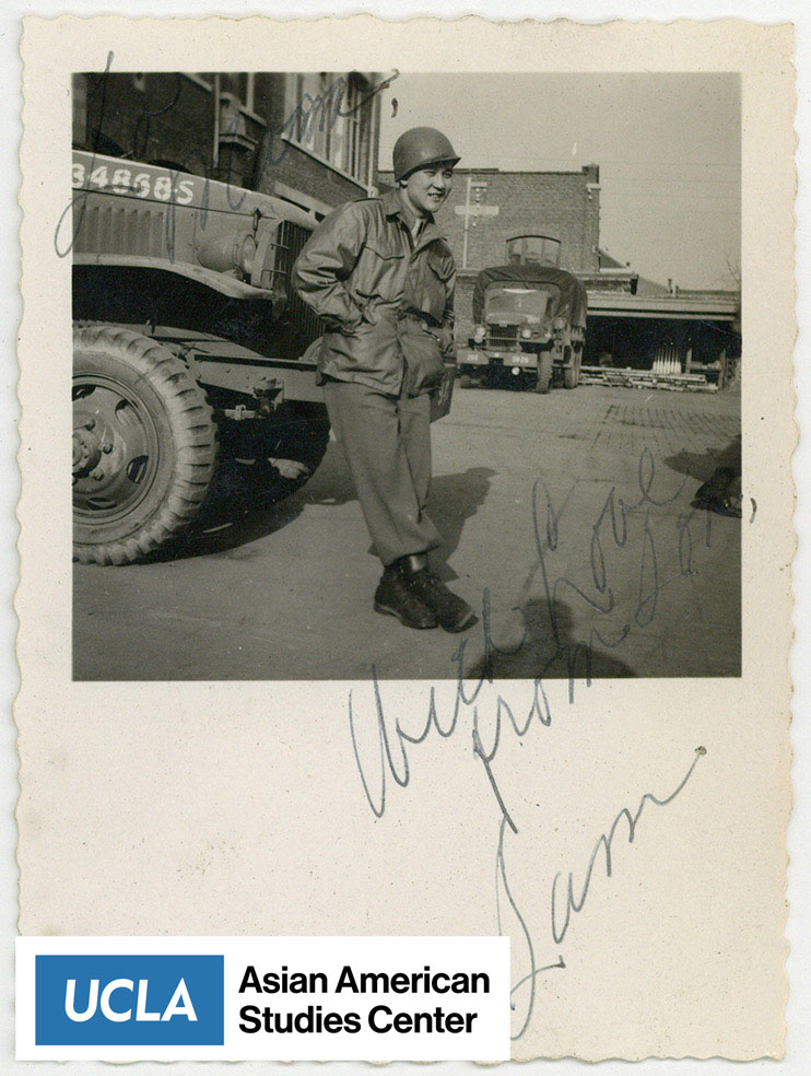 Nisei solider in military uniform standing next to truck. Includes text: 