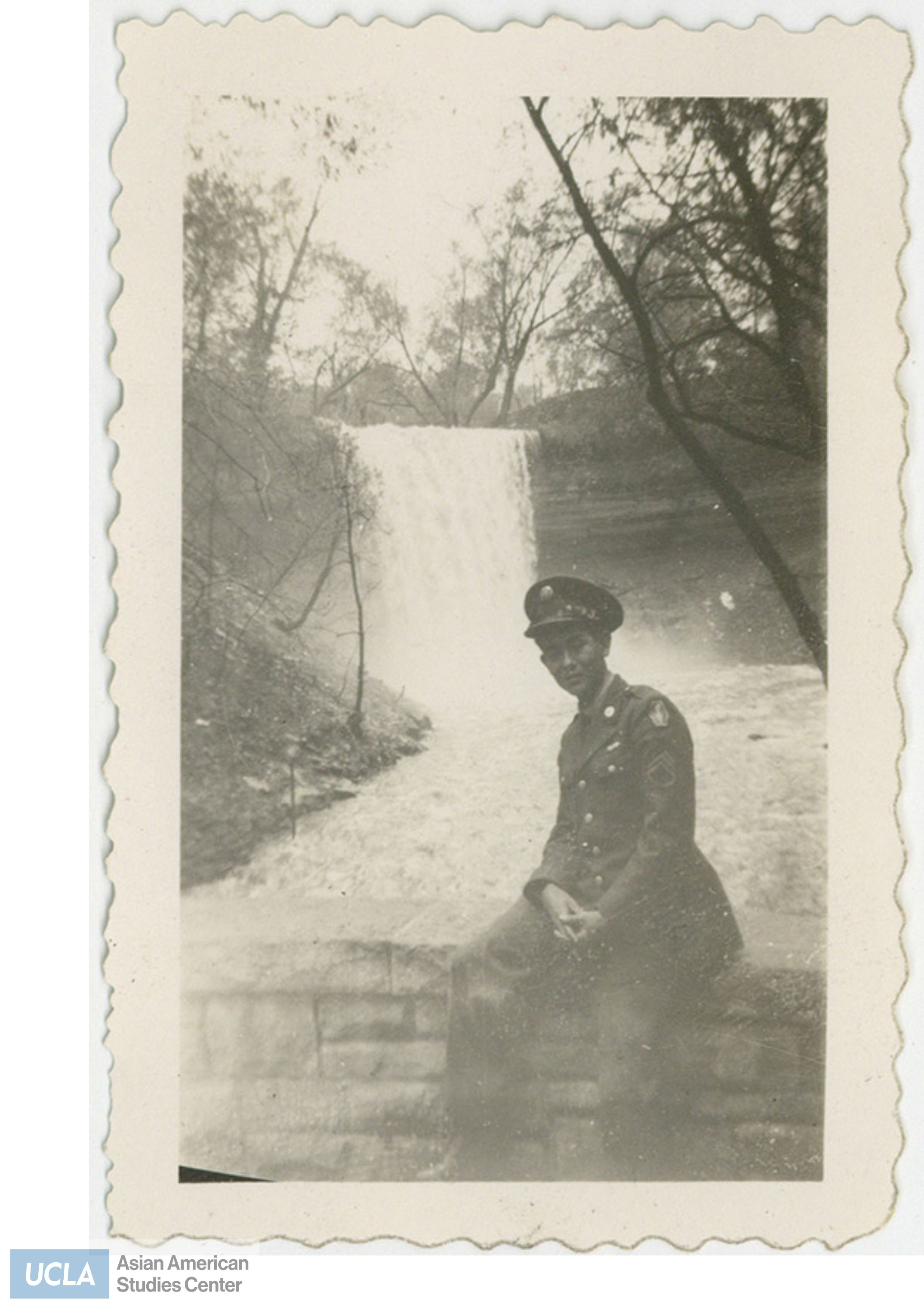 Nisei solider sits infront of waterfall at Minnehaha Falls.