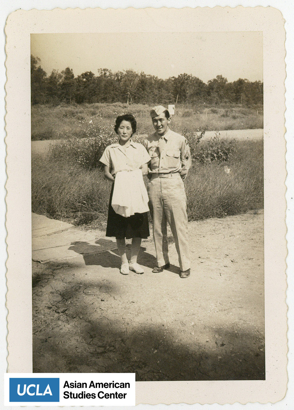 Tsuma Nakahara standing to the left of a Nisei man in uniform.