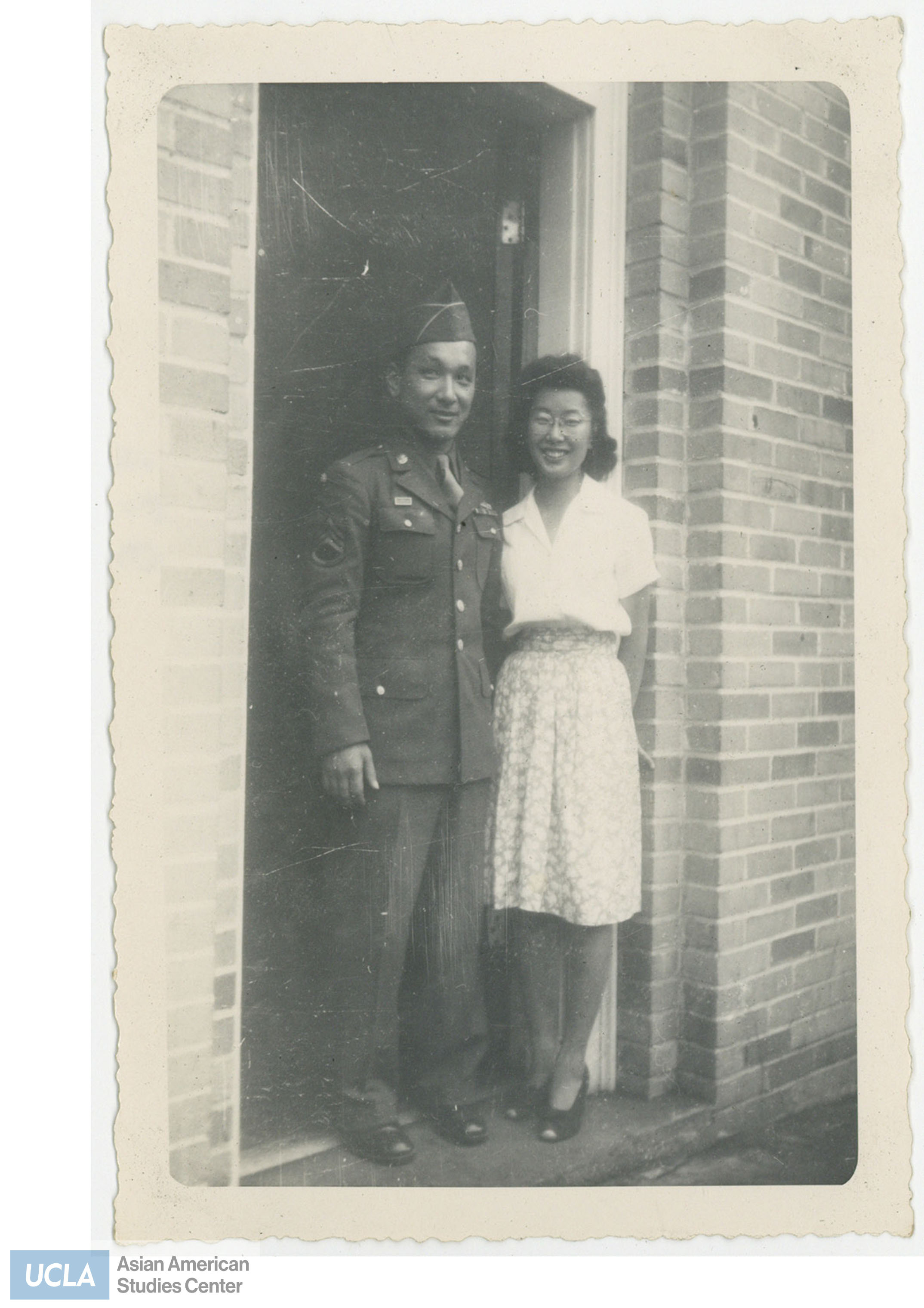 Tom and Yuri stand in a doorway. Back of photo includes text: 