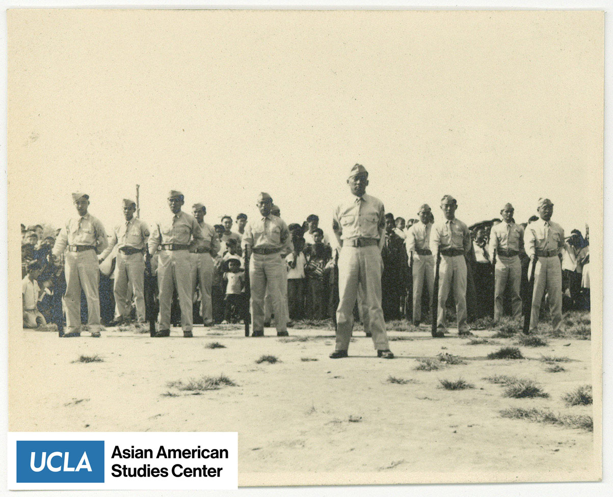 Nisei serviceman stand at ease with rifle in hand.