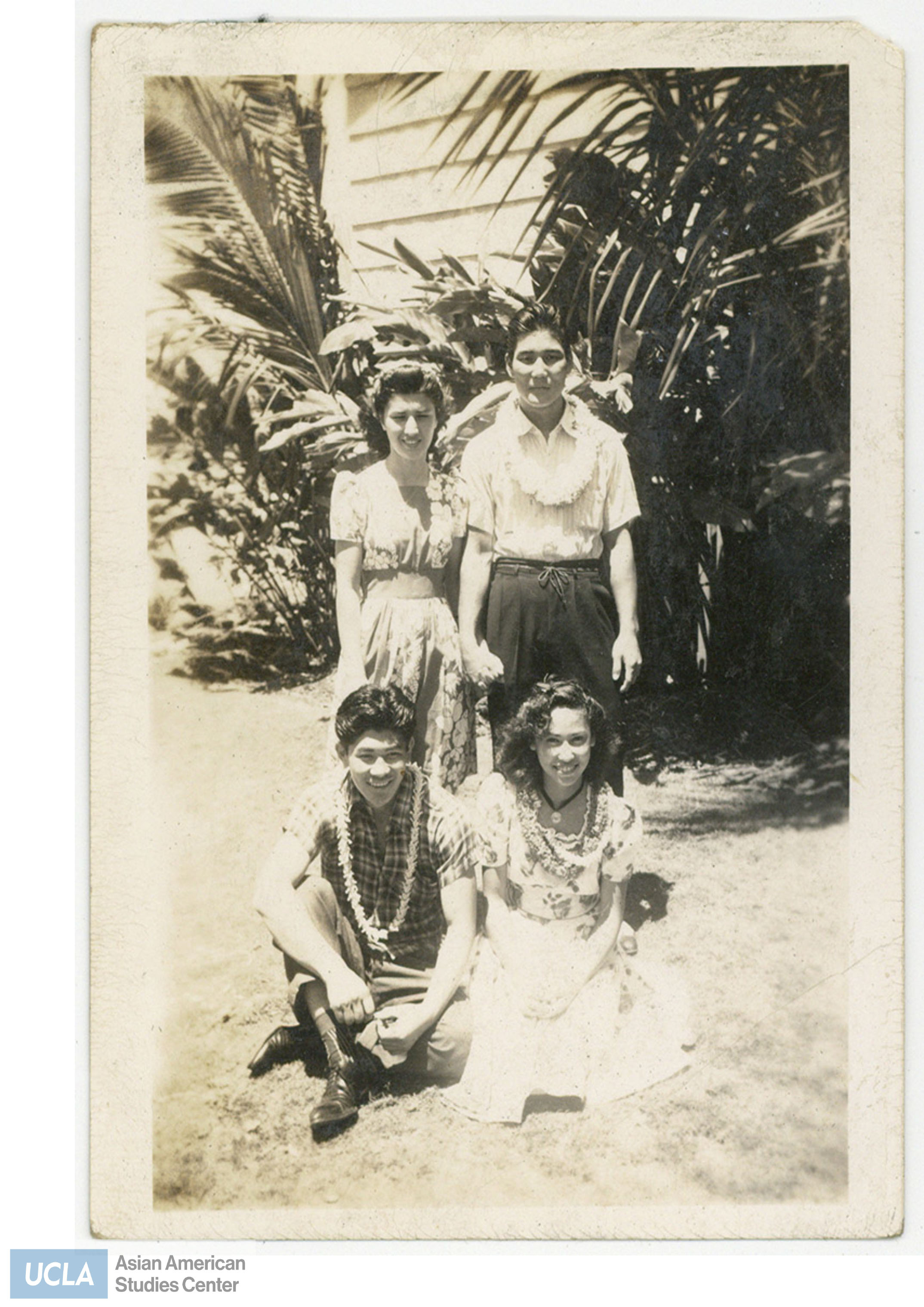 Young people wearing flower leis. Back of photo states the date and names of people in the photo.
