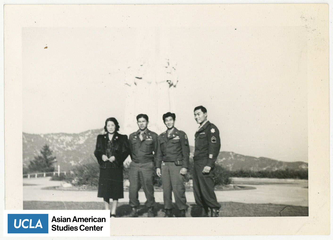 Tsuma and three Nisei servicemen stand for a photograph. Haru stands in the center between the two Nisei men.