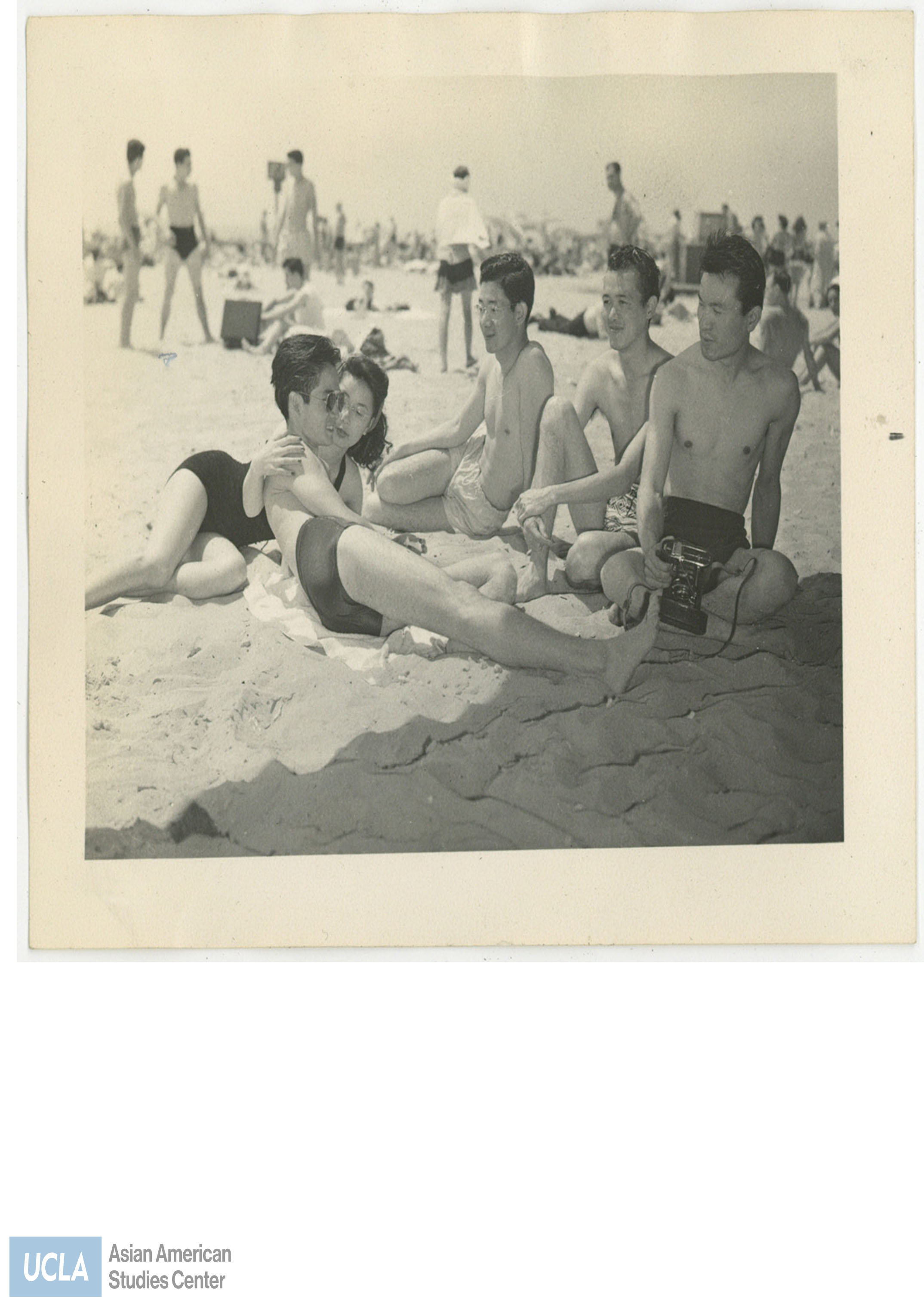 Group of Nisei laying on the beach. Back of photo includes text: 
