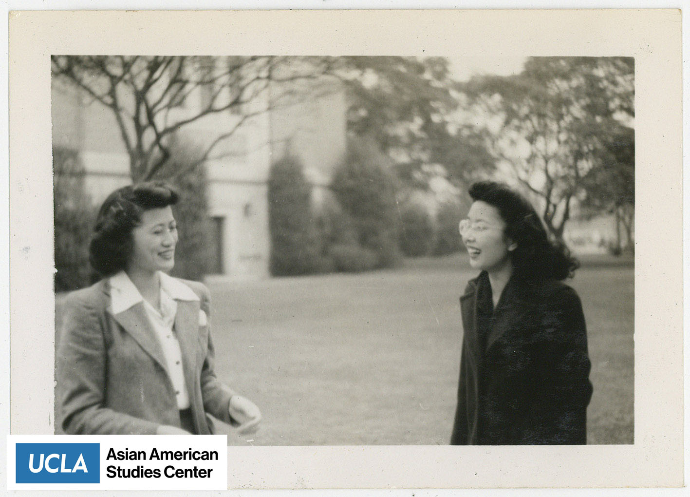 Possibly Tsuma Nakahara and Yuri standing outside with trees and a building in the background.