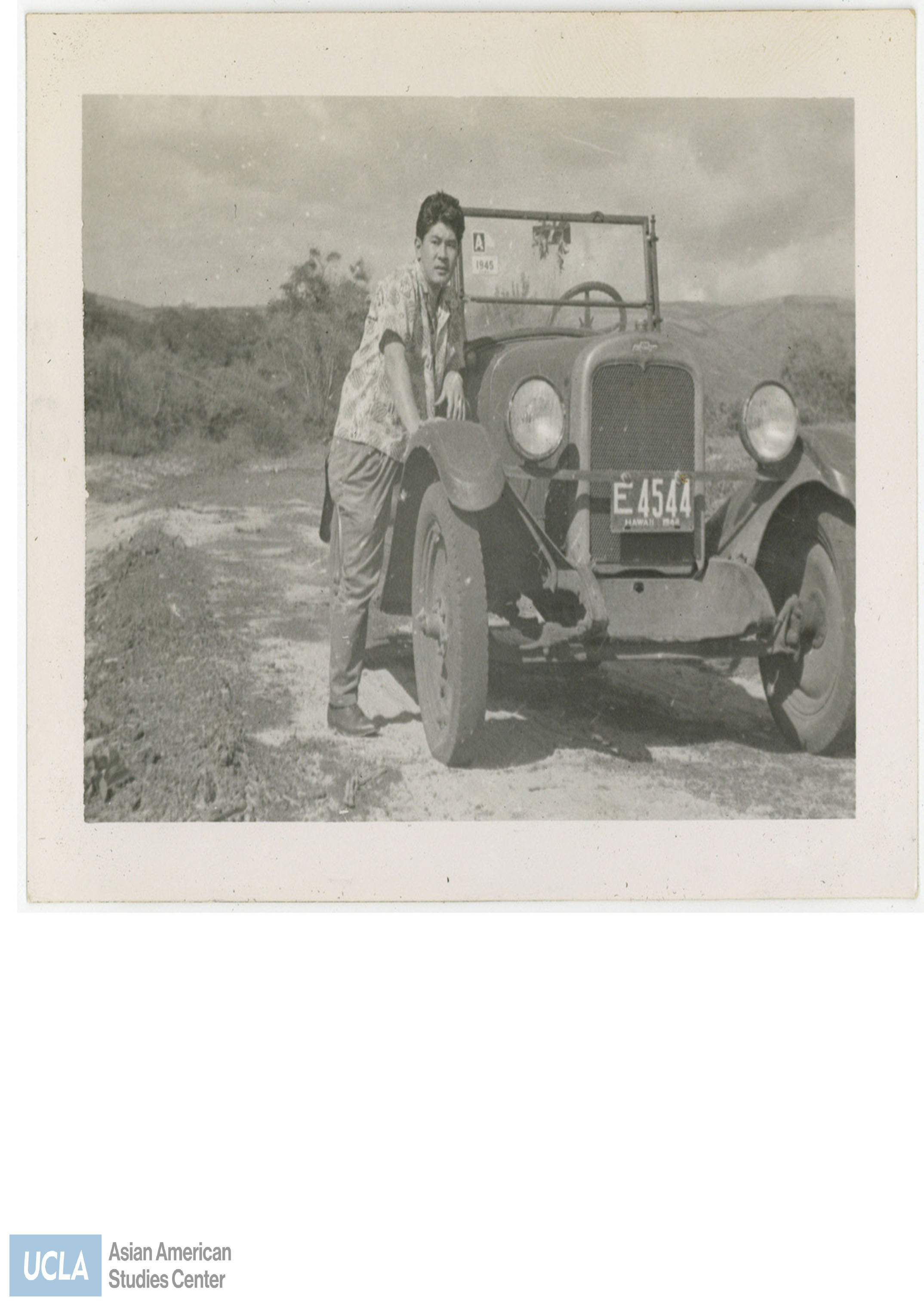 Man leaning against a car with license plate 