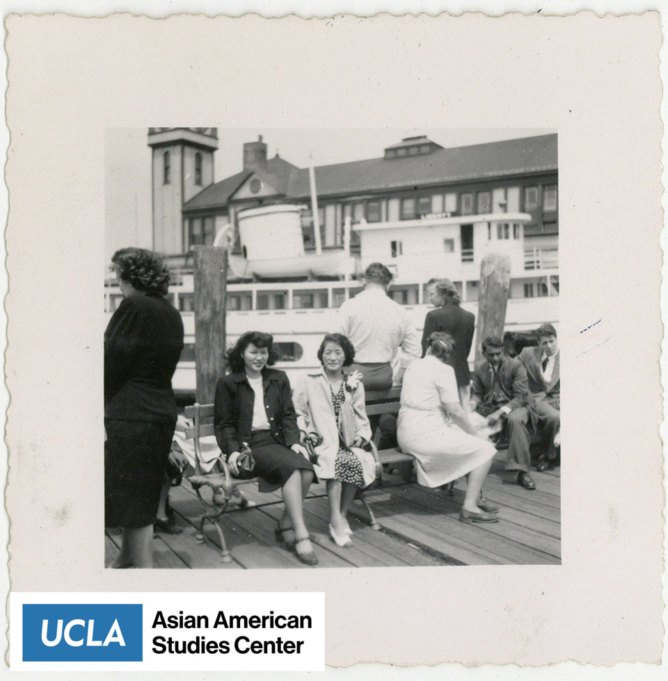 Tsuma and friend sit on a bench at the pier.