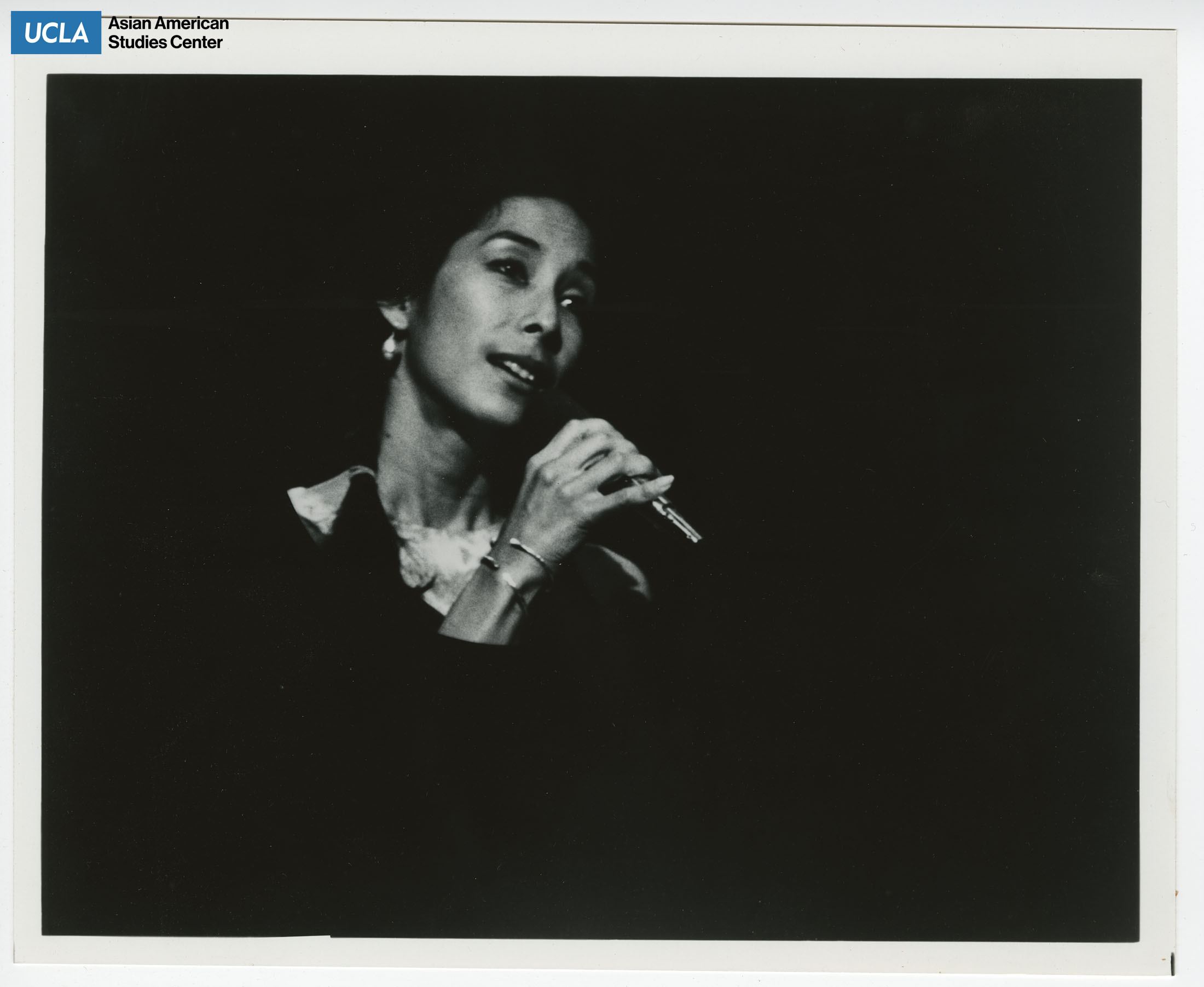 Nobuko Miyamoto sings with a microphone during a performance.