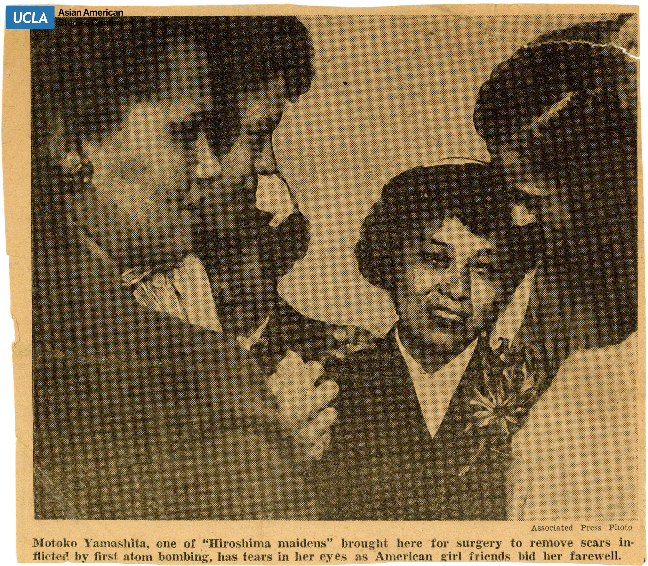 Newspaper clipping photo of women providing comfort to a teary Motoko Yamashita of Hiroshima Maidens.