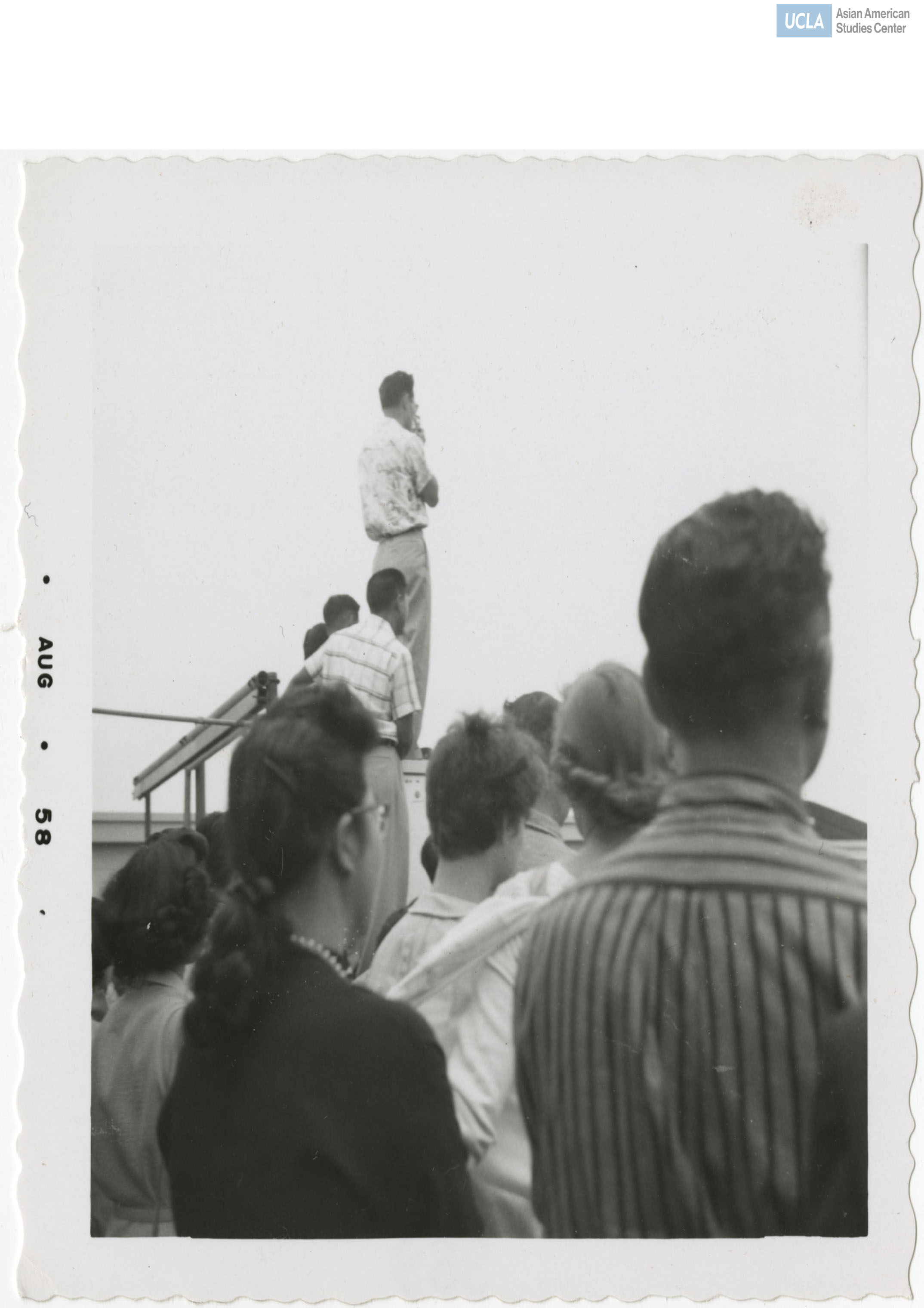 Welcoming party greet attendees while a man is standing on an elevated platform for a better view.