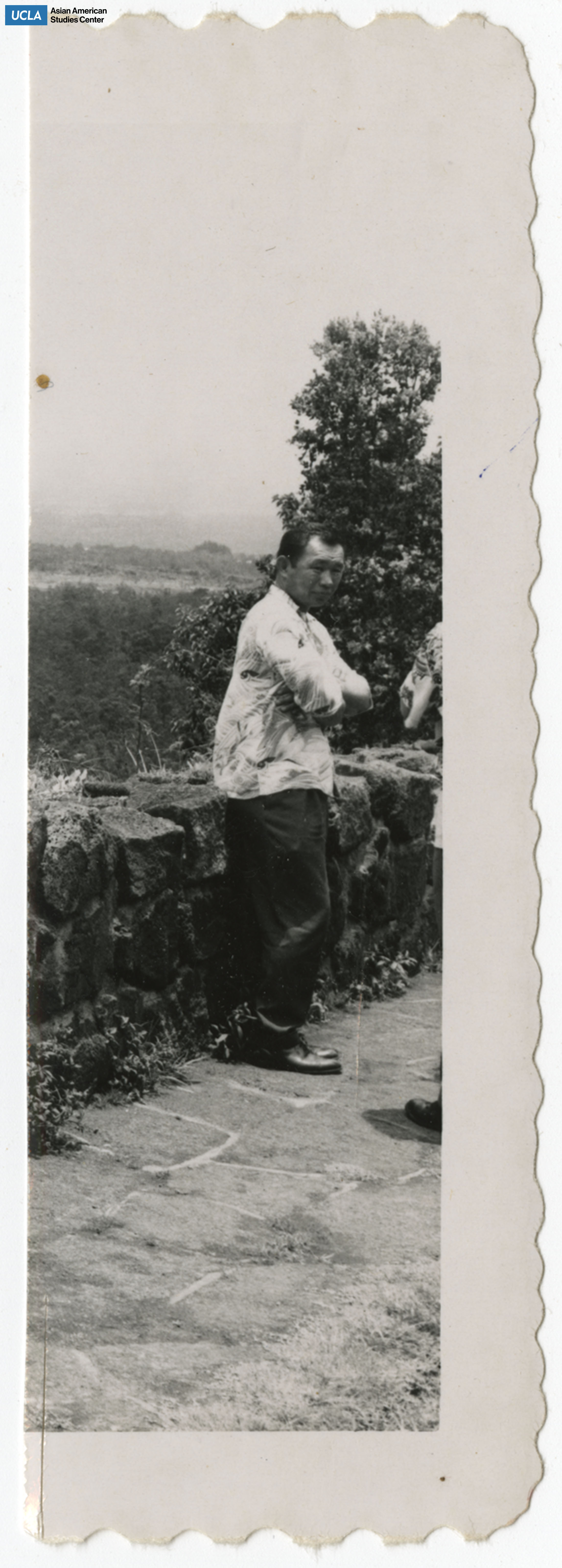 Man stands with arms crossed infront of a rock wall.