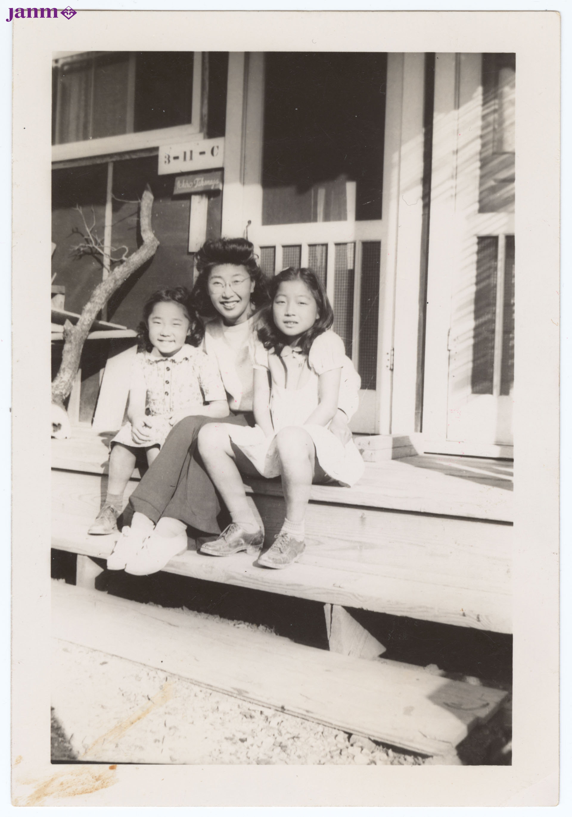 At Camp Rohwer, Yuri and two girls sitting on steps of barrack 3-11-C.